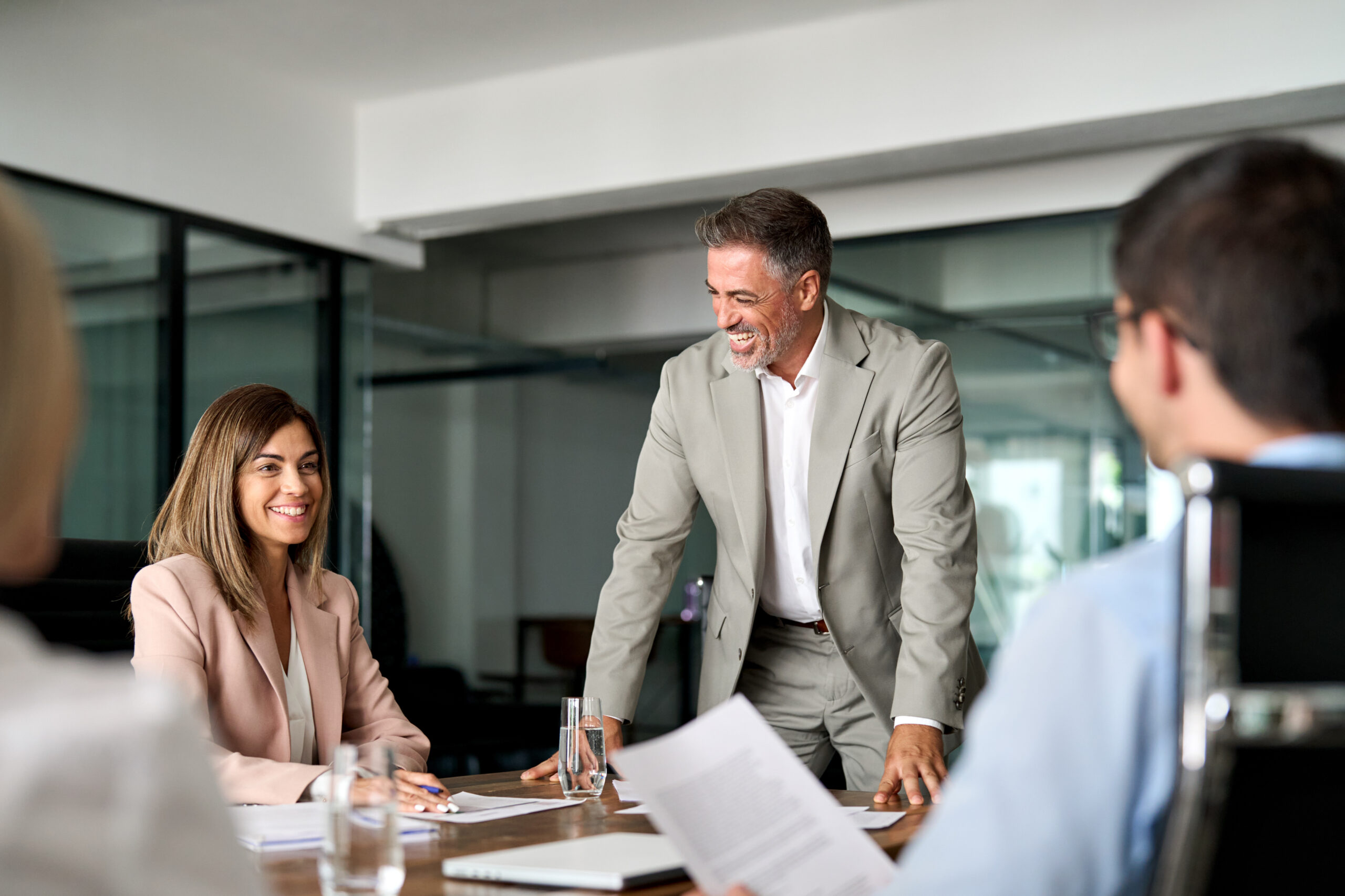 Happy executive manager and board team people having discussion at office meeting. Mature old business man CEO leader talking to workers at group corporate meeting in boardroom working together.
